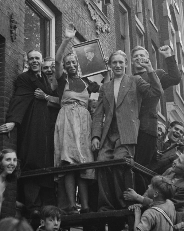 Een kaalgeschoren vrouw wordt gedwongen het portret van Hitler te groeten