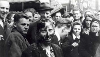 Een kaalgeschoren en met pek besmeurde 'moffenmeid' wordt door omstanders uitgejouwd