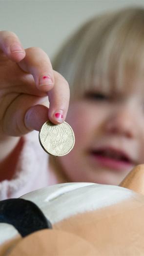 een kind doet geld in een spaarpot