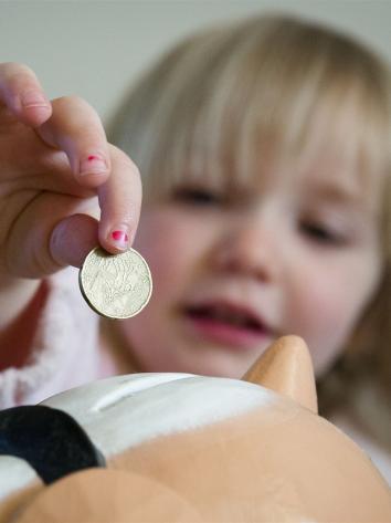 een kind doet geld in een spaarpot