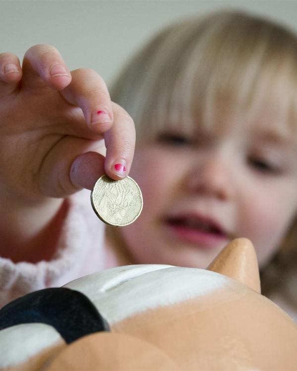 een kind doet geld in een spaarpot