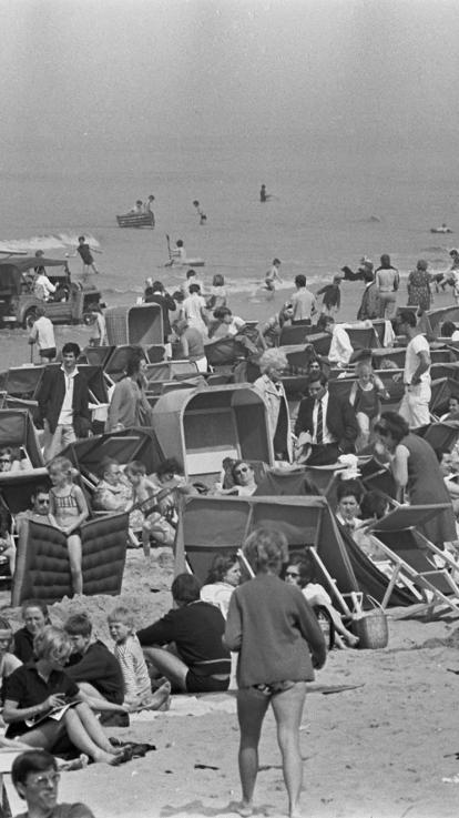 Een zwart-witfoto van een drukbezocht strand in Nederland