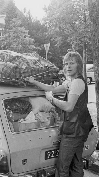Een zwart-witfoto van twee vakantiegangers die hun auto aan het volladen zijn 
