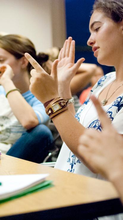 Groep mensen in een klaslokaal spreken allemaal met gebarentaal