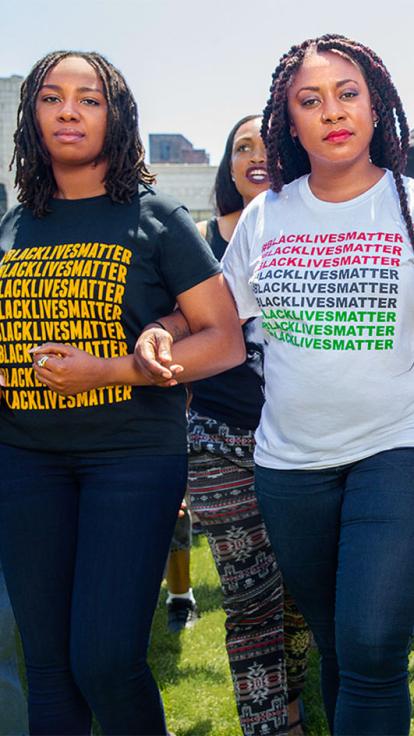 vrouwen arm in arm met 'Black Lives Matter' shirts aan bij een demonstratie