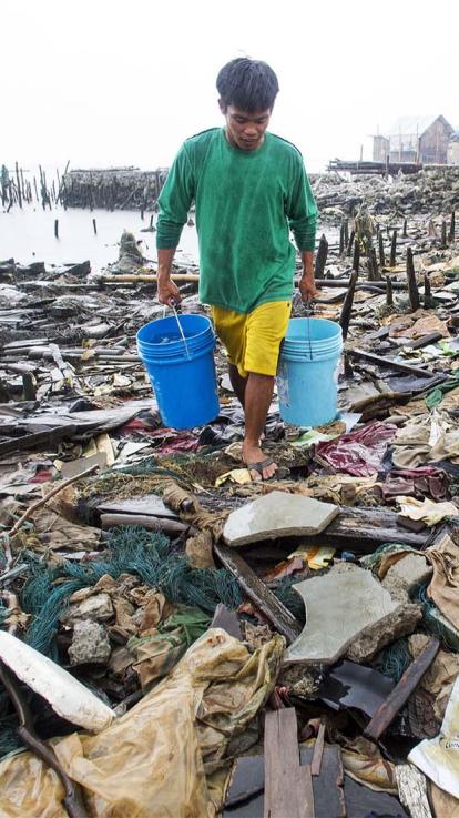 iemand loopt met lege emmers door een zee van afval