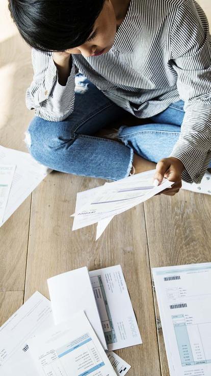 Vrouw zit op de grond tussen de boetes en aanmaningen