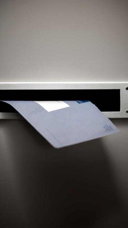 Blauwe brief valt in de brievenbus