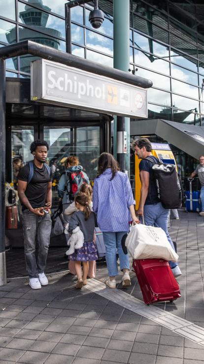 reizigers bij de ingang van Schiphol