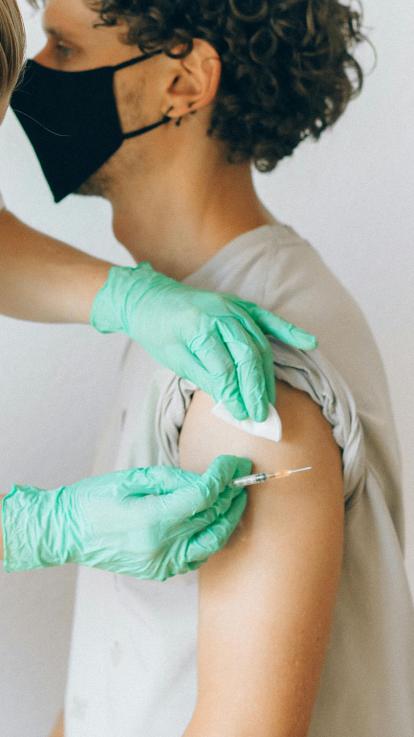 Jongen met mondkapje wordt gevaccineerd