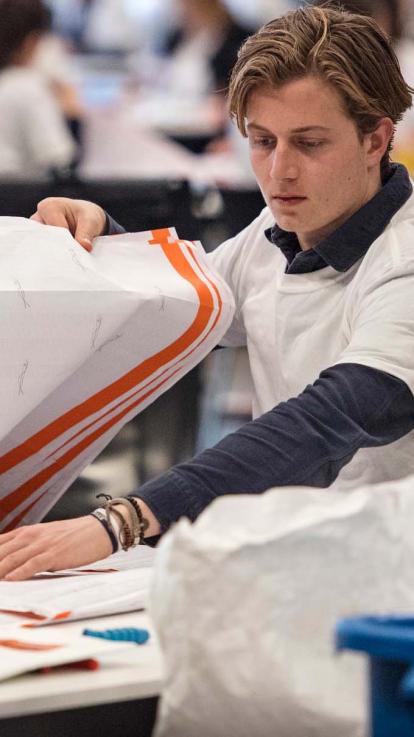 iemand sorteert stembiljetten aan een tafel