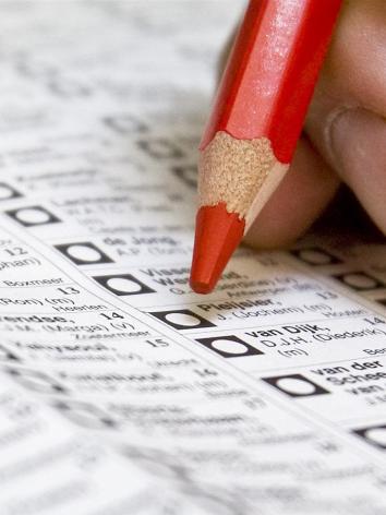 hand met rood potlood boven een stembiljet