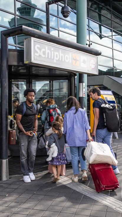 Reizigers bij de ingang van Schiphol
