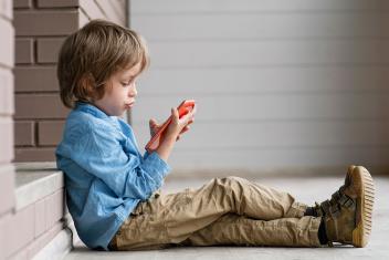 kind kijkt op het scherm van de mobiele telefoon