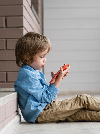 kind kijkt op het scherm van de mobiele telefoon