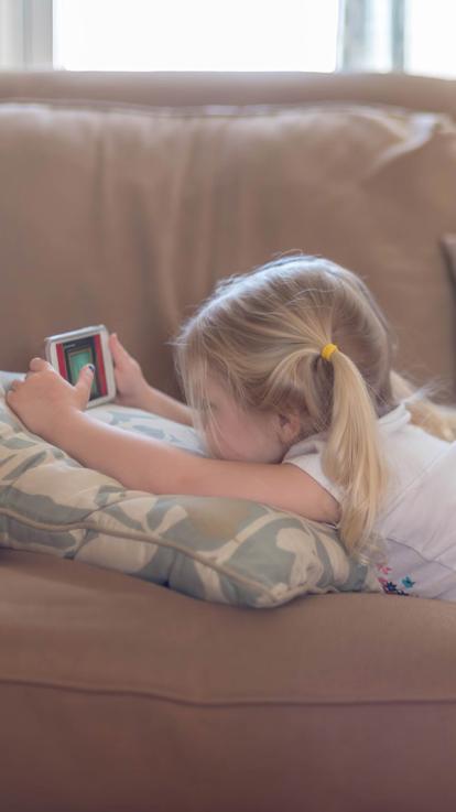 een klein meisje achter een scherm op de bank