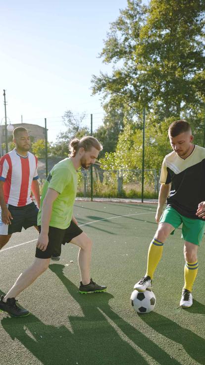 Drie mannen samen aan het voetballen in een woonwijk