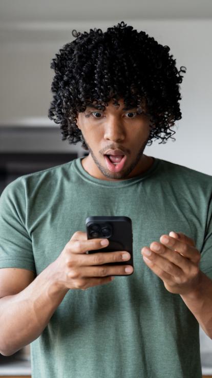 Man kijkt geschokt naar zijn telefoonscherm