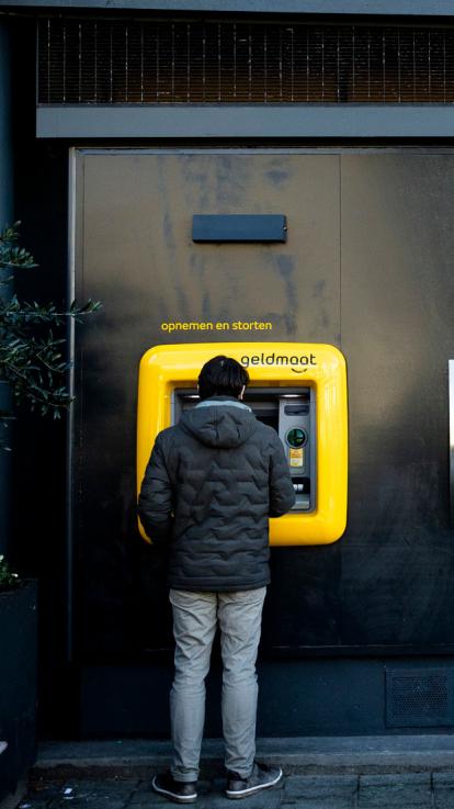iemand neemt geld op bij een geldautomaat