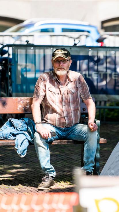 Een man zit op een bankje in de stad