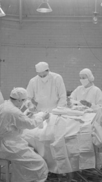 Zwart wit foto van een operatiekamer waar het personeel mondkapjes draagt 