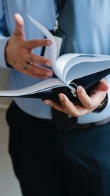 een persoon in pak bladert een dossier door
