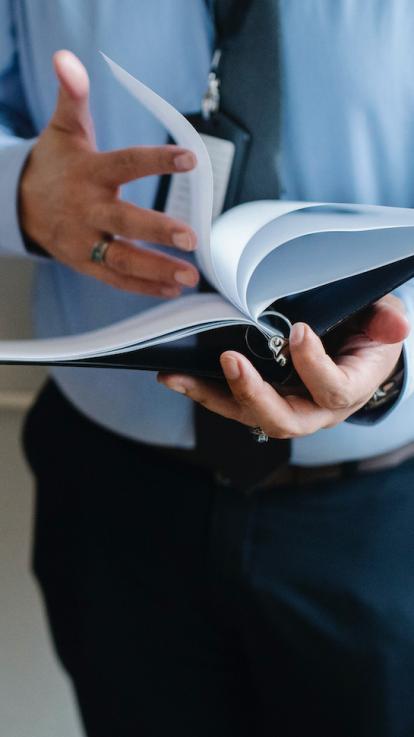 een persoon in pak bladert een dossier door