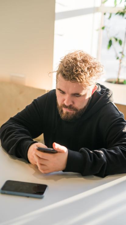 een man kijkt aandachtig naar de telefoon in z'n hand