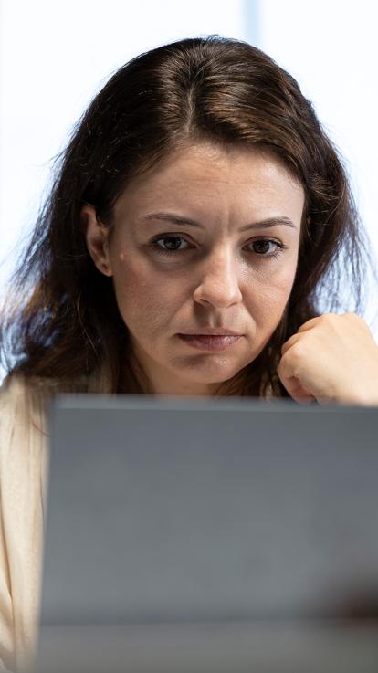 Een vrouw kijkt serieus naar iets op haar laptop