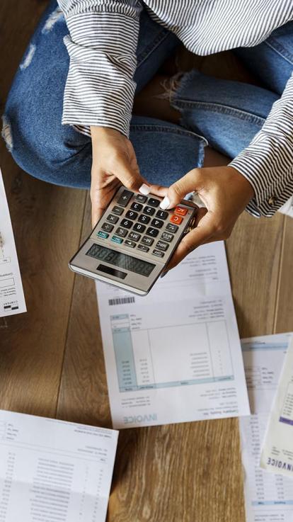 iemand met papieren en een rekenmachine op de grond