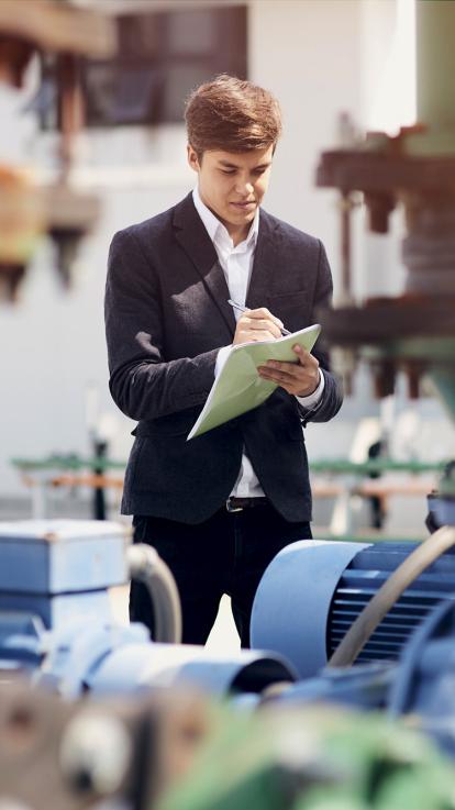 een curator schrijft iets op een papier terwijl hij de inboedel van een bedrijf bekijkt