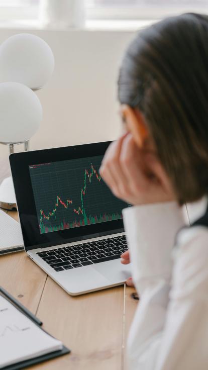 Een vrouw kijkt naar haar laptop waar informatie staat over koersen