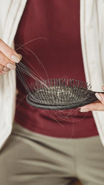 vrouw met haaruitval trekt haren uit borstel