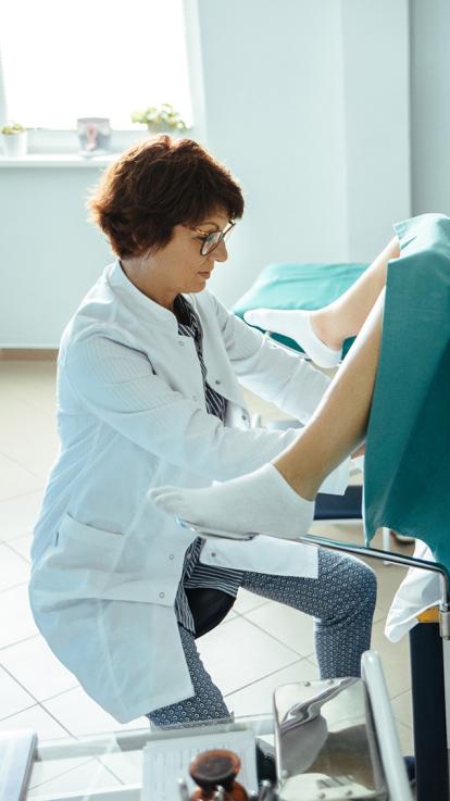 Gynaecoloog kijkt naar vrouw die in behandelstoel zit met benen wijd 