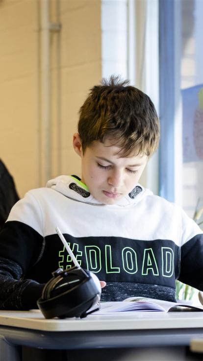 jongen in de schoolklas aan zijn huiswerk