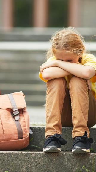 verdrietig meisje met schooltas