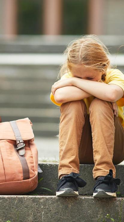 verdrietig meisje met schooltas