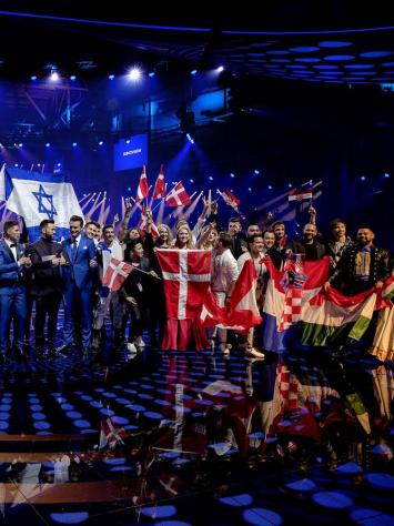 Verschillende deelnemers van het songfestival op het podium met vlaggen van hun land