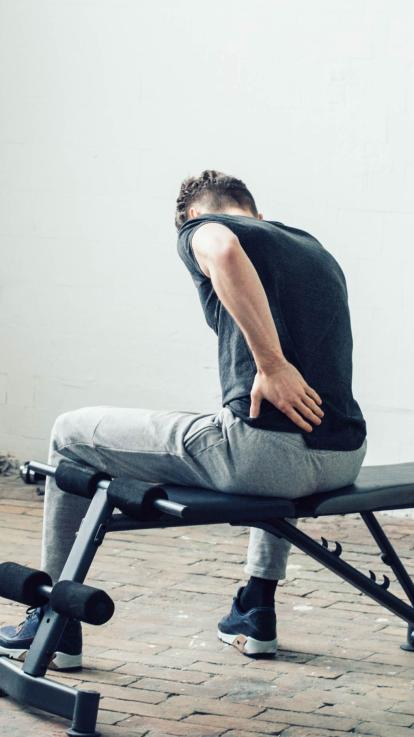 man met spierpijn in de sportschool