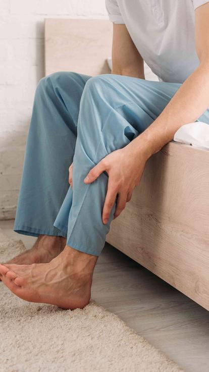 man met spierpijn in been stapt uit bed