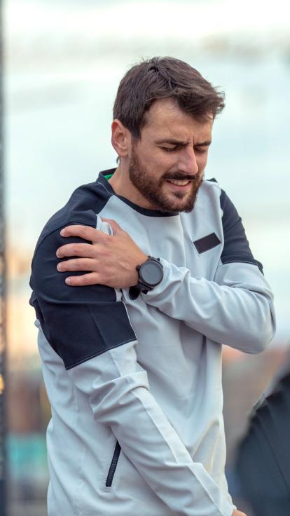 een man in sportkleding grijpt naar zijn bovenarm