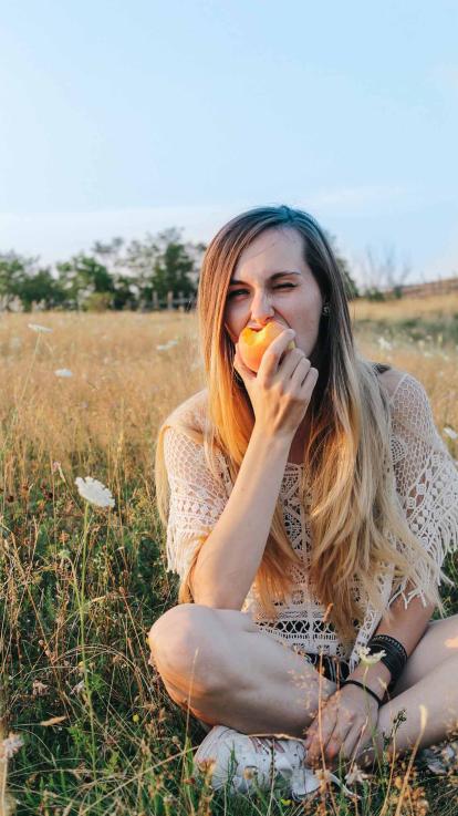 iemand eet een appel in een weiland