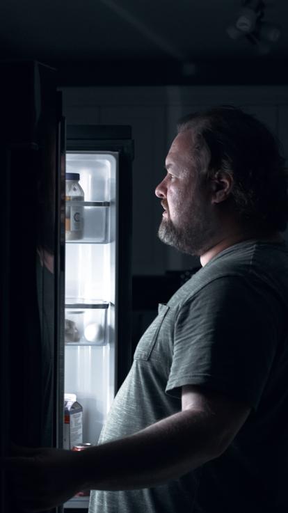 man met overgewicht zoekt in ijskast naar eten 