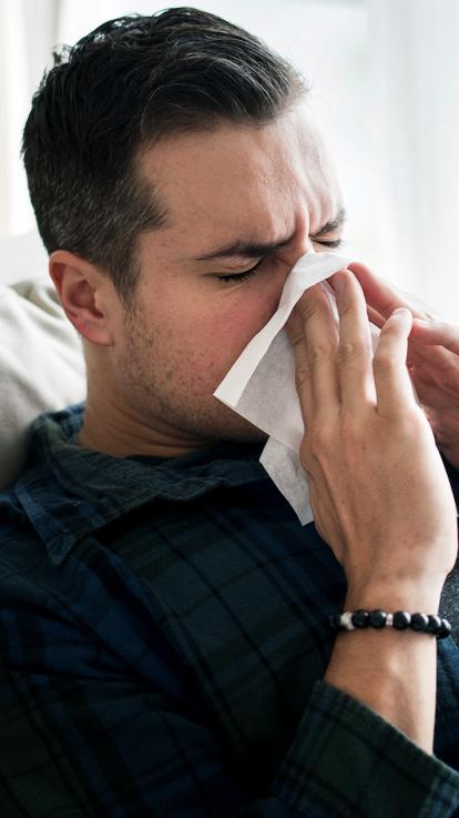 een man is ziek en snuit zijn neus in een tissue