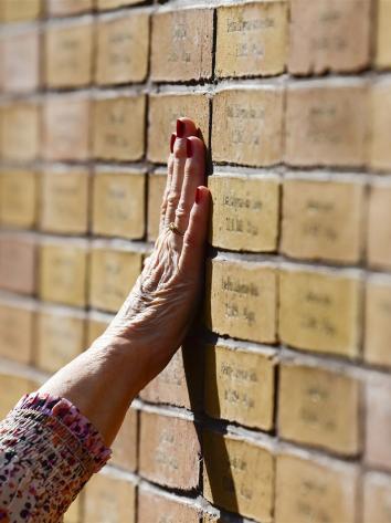 Een vrouw legt haar hand op het Nationaal Holocaust Namenmonument