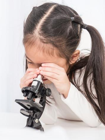 een kind kijkt door een microscoop 