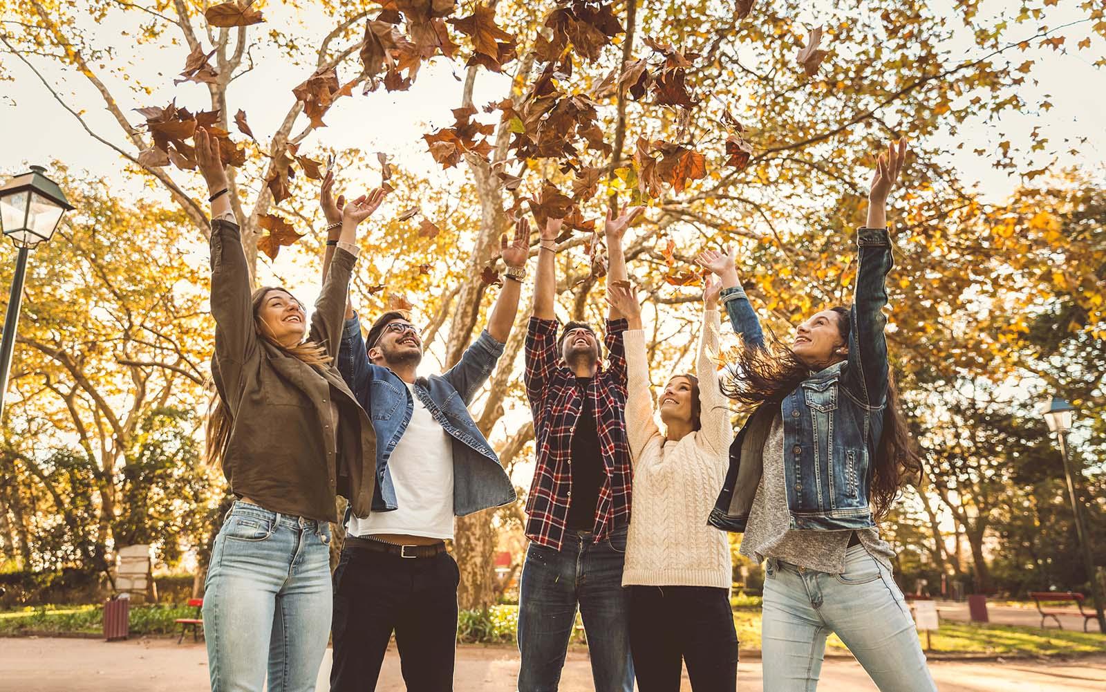 Mensen gooien herfstblaadjes in de lucht herfst
