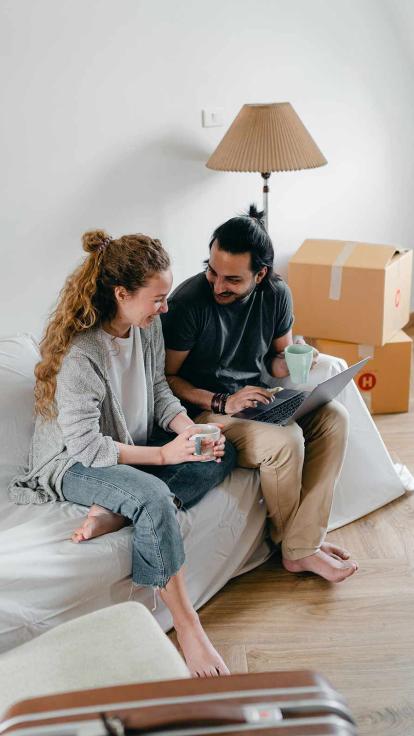 Man en vrouw zitten samen op de bank in een huis, ze zijn thuis en gelukkig.