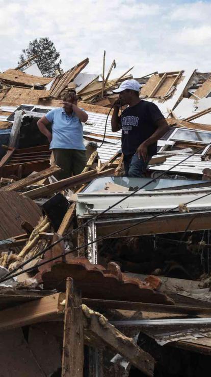 Man en vrouw kijken ontredderd naar de schade aan hun woningen na een orkaan