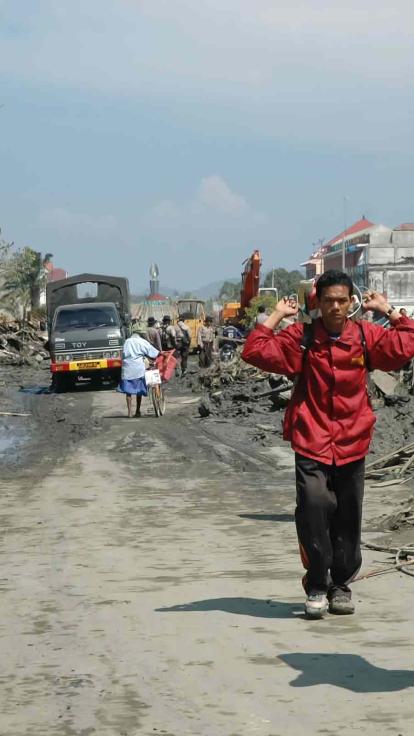 Mensen lopen met spullen door puin en verwoeste straat na een orkaan